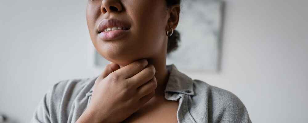 Woman with a sore throat and holding her throat