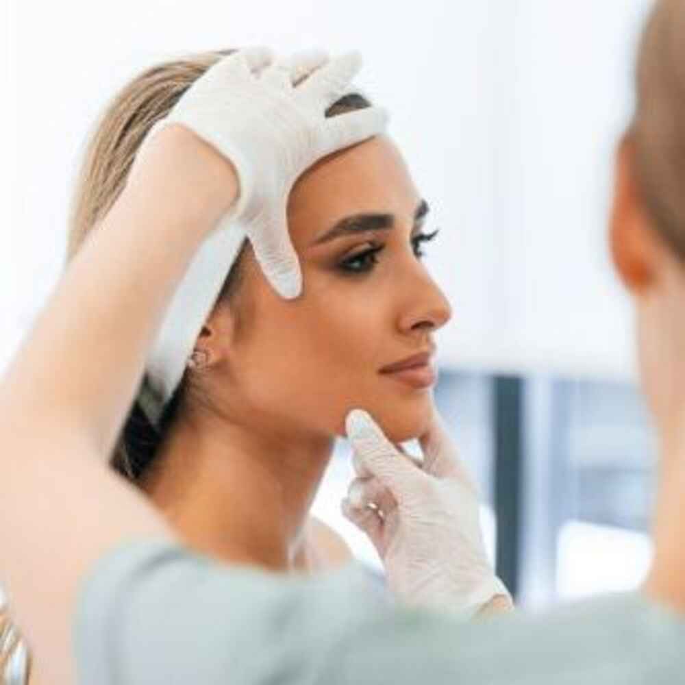 Facial plastic surgeon examining patient's face