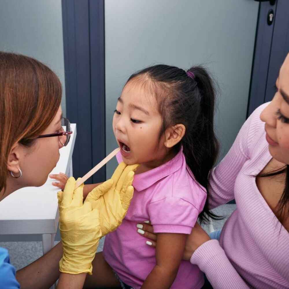 ENT doctor checking child's mouth and throat for tonsillitis
