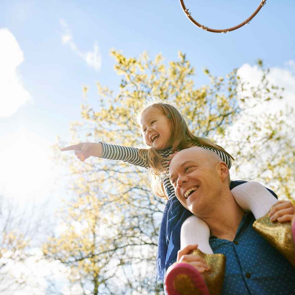 Father carrying daughter on shoulders while being free of allergies