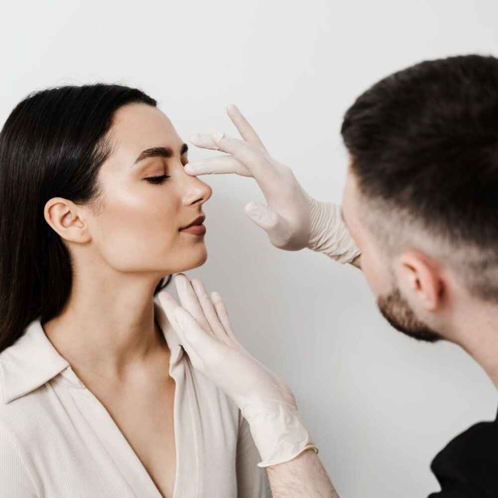 Facial plastic surgeon touching and examining nose for rhinoplasty nose job