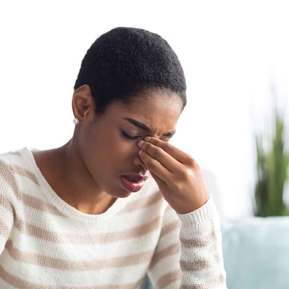 Woman experiencing sinusitis and grabbing her nose