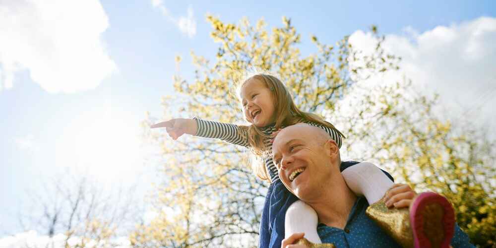 Father carrying daughter on shoulders while being free of allergies