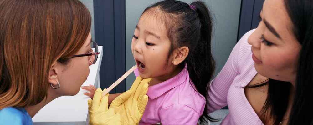 ENT doctor checking child's mouth and throat for tonsillitis
