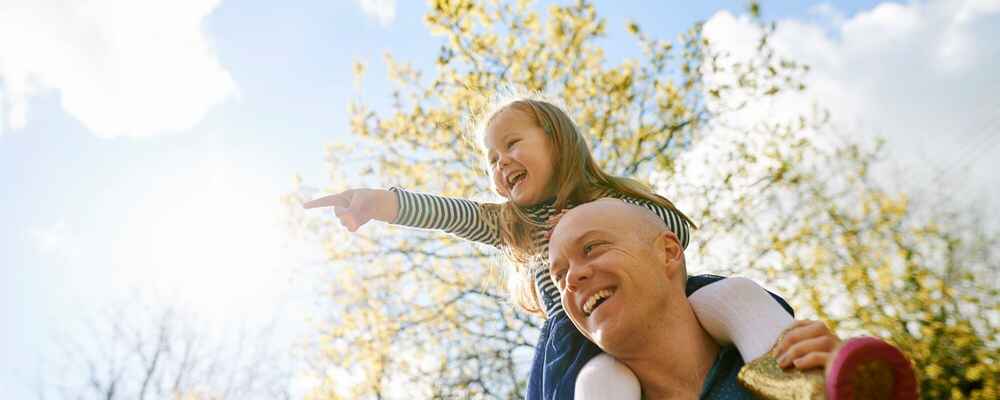 Father carrying daughter on shoulders while being free of allergies