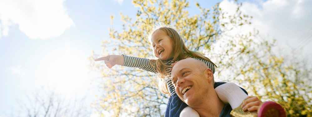Father carrying daughter on shoulders while being free of allergies